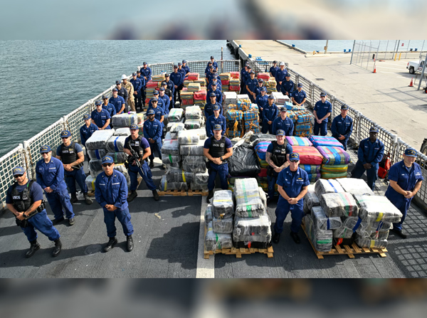 USCGC Valiant (WMEC 621) crew members pause for a group photo with pallets of drugs before offloading at Port Everglades in Fort Lauderdale, Florida, June 6, 2025. The Valiant crew offloaded more than $132 million in illicit drugs interdicted in the Caribbean Sea. (U.S. Coast Guard photo by Petty Officer 1st Class Diana Sherbs)